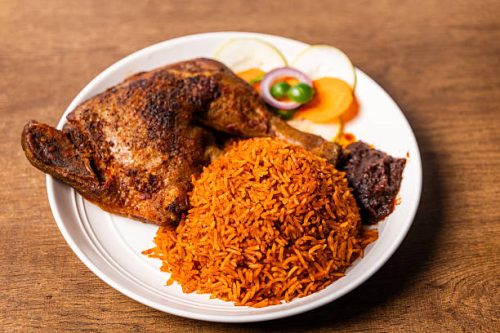 Ghanaian Jollof Rice with Grilled Chicken, Long-grain rice cooked in a rich tomato and pepper sauce, a popular traditional dish from West Africa